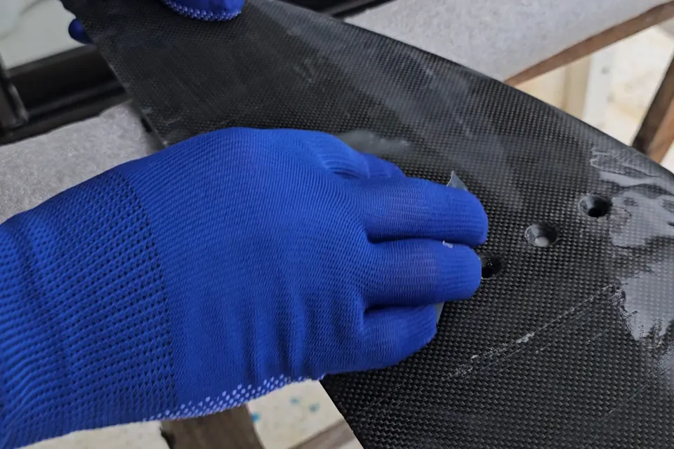 Hand sanding around the mounting holes of a carbon front wing